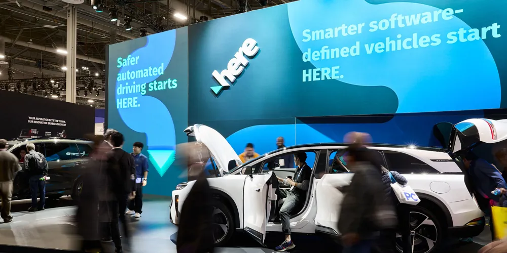 HERE Technologies’ booth at CES 2026, featuring their Software-Defined Vehicle Maturity Framework in a car. Around the booth and vehicle is a bustling crowd.