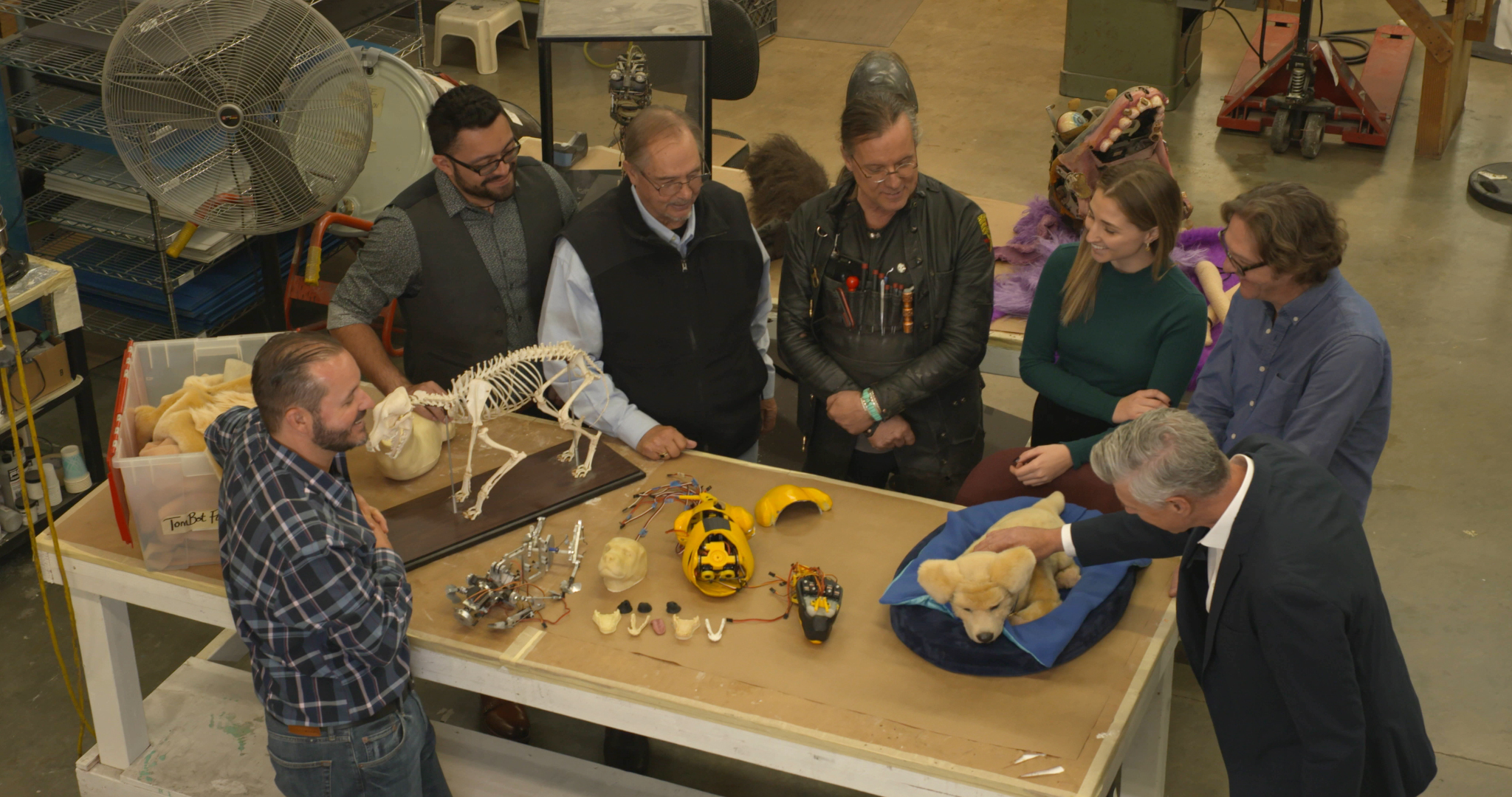 Alt Text: Tombot visits Jim Henson’s Creature Shop to update the look of Tombot’s robotic emotional support companion puppy Jennie.