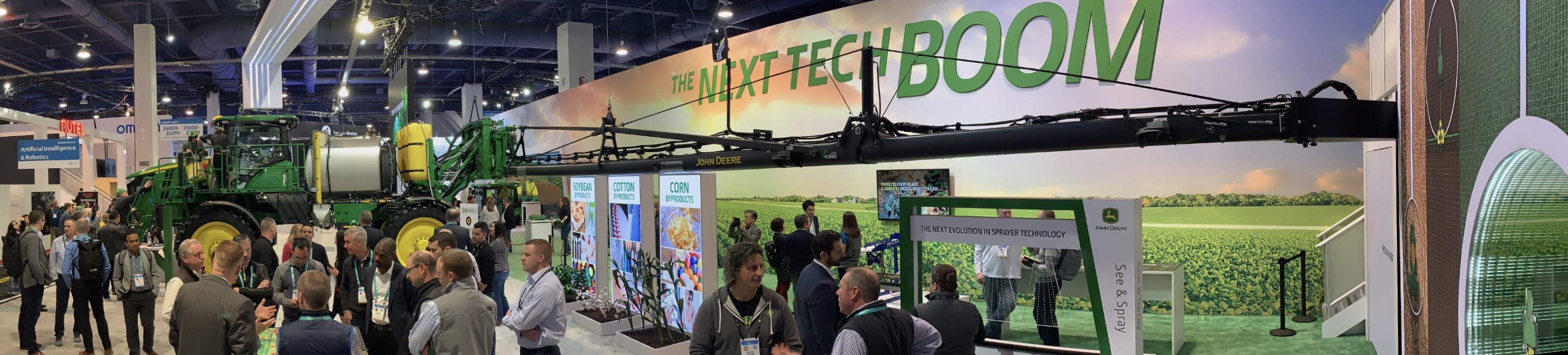 ALT Text: a panoramic view of John Deere's booth at CES with the banner saying the next tech BOOM
