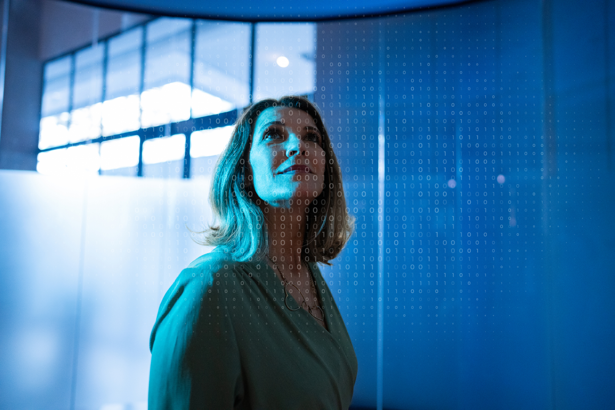 ALT Text: A woman looking up with a bunch of zeros and ones filtered in front